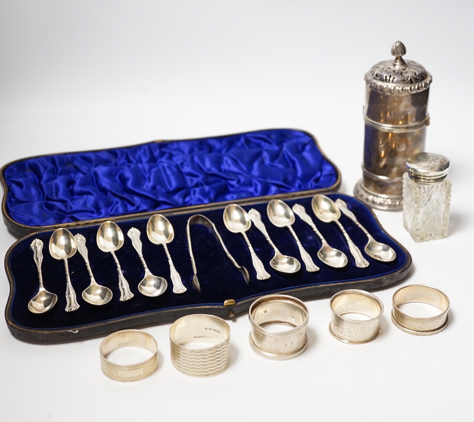 A cased set of twelve late Victorian silver teaspoons with tongs, William Hutton & Sons, London, 1898, a late Victorian silver lighthouse sugar caster, London, 1889, five assorted silver napkin rings and a silver mounted
